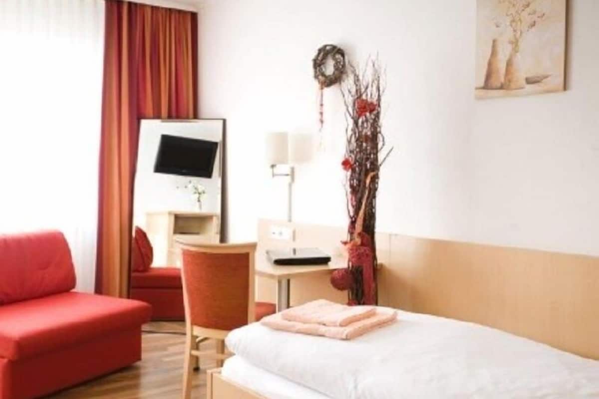 A hotel room with a bed, a desk, a chair, and a TV.