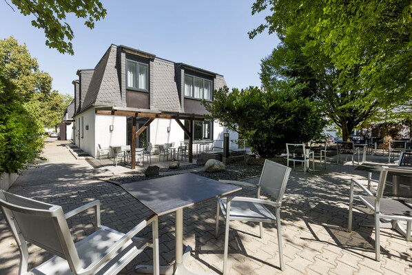 Una casa moderna con un patio que cuenta con mobiliario exterior y un sendero de piedra.