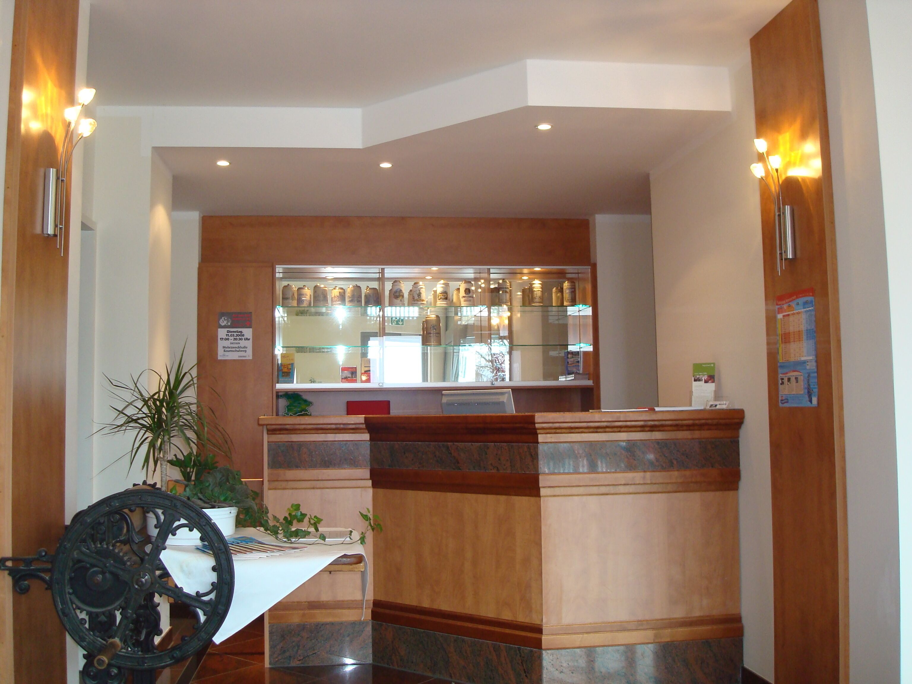 A reception area with a wooden counter, a glass display case, and a potted plant.