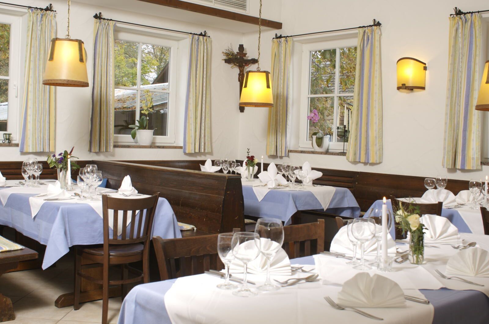 A restaurant with multiple tables set for dining, featuring blue tablecloths and white napkins.