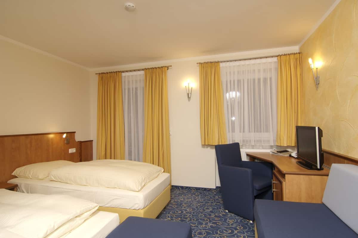 A hotel room with two beds, a desk with a computer, and a chair.