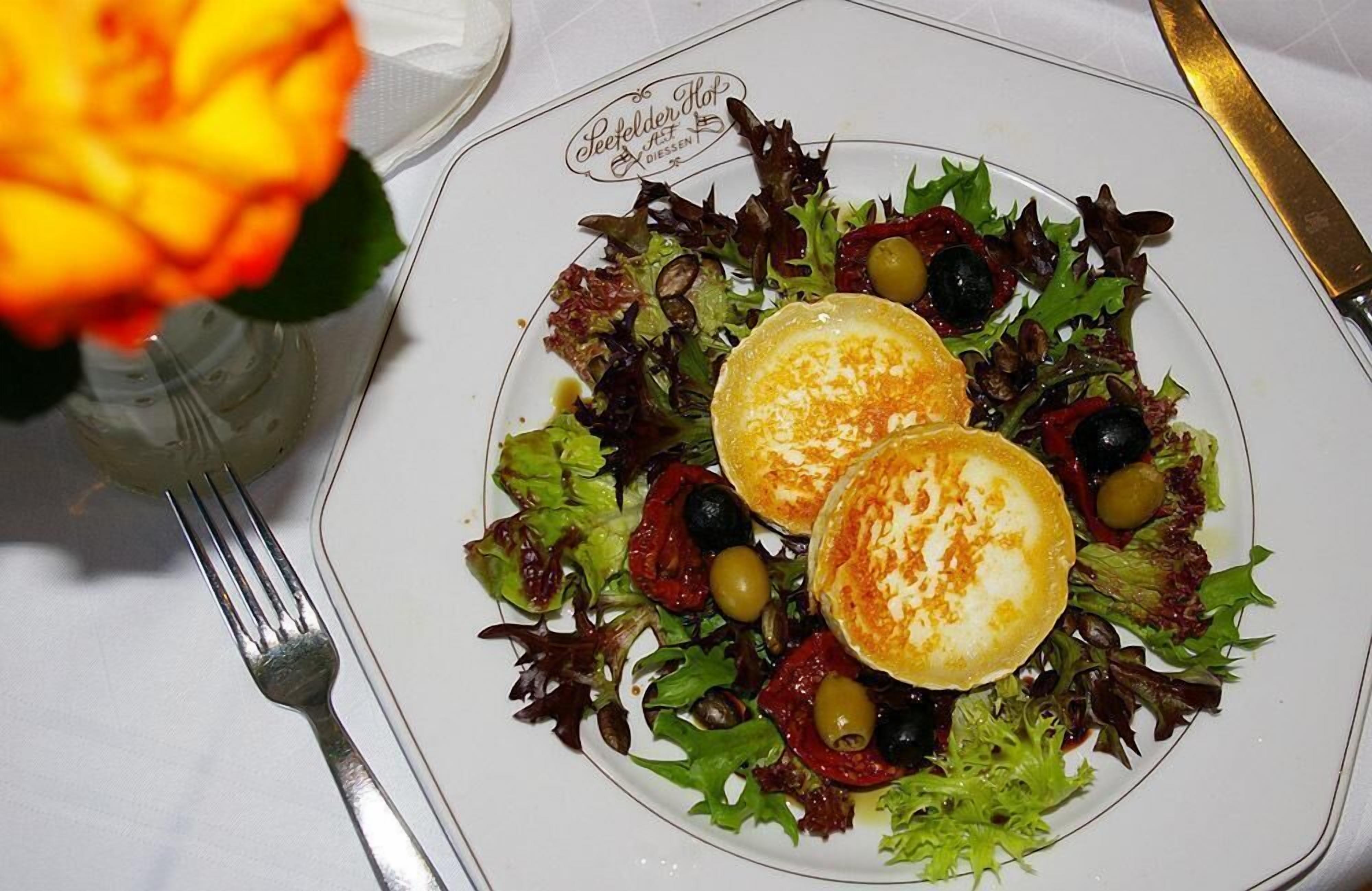 A plate of food with a salad and two poached eggs on a white plate with a logo.