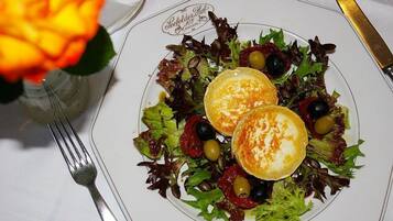 A plate of food with a salad and two poached eggs on a white plate with a logo.