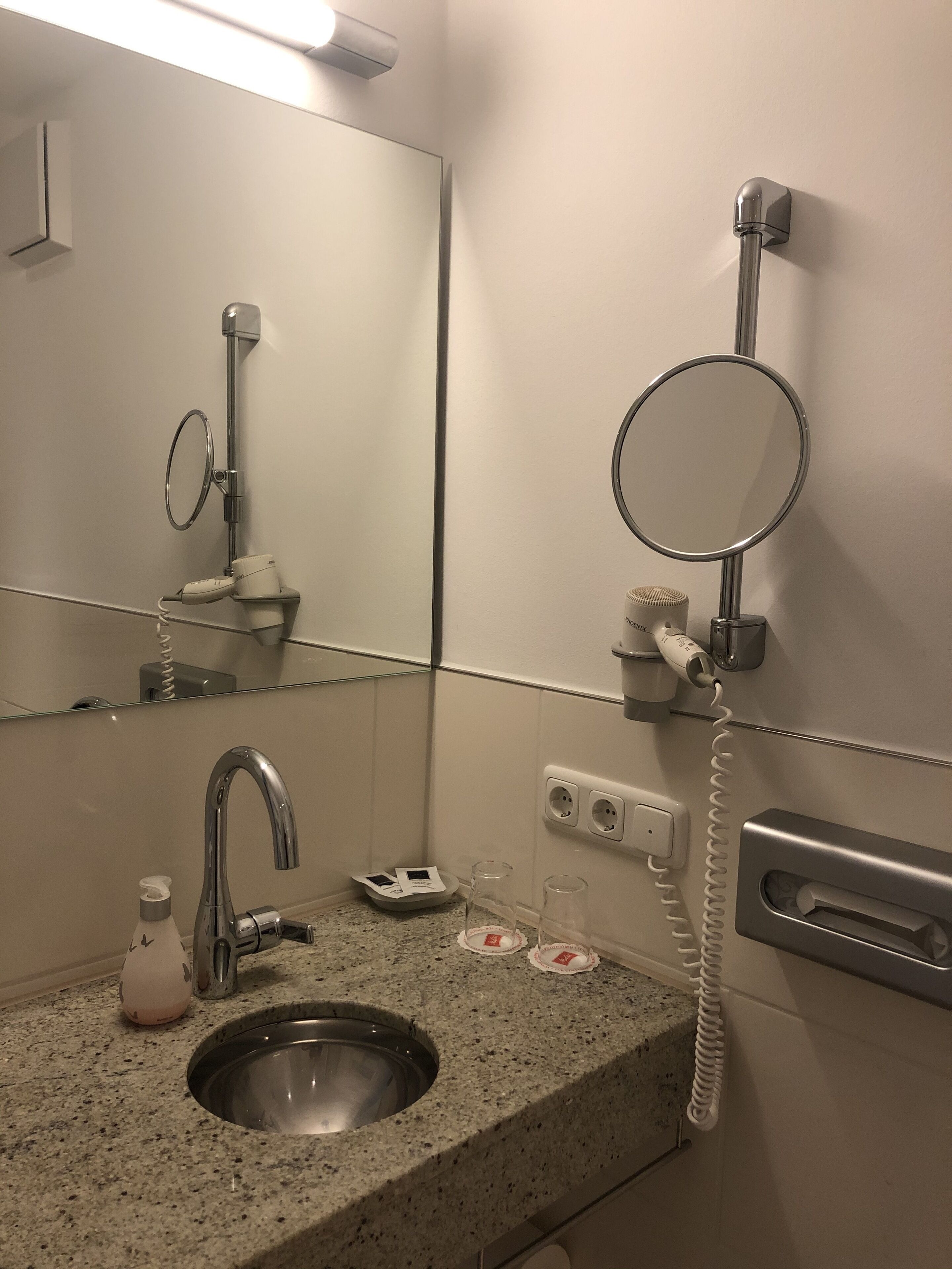 A bathroom with a sink, mirror, hairdryer, and towel rack.