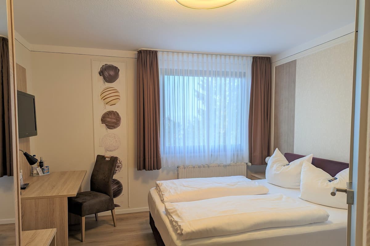 Een hotelkamer met een bed, een bureau, een stoel en een televisie.