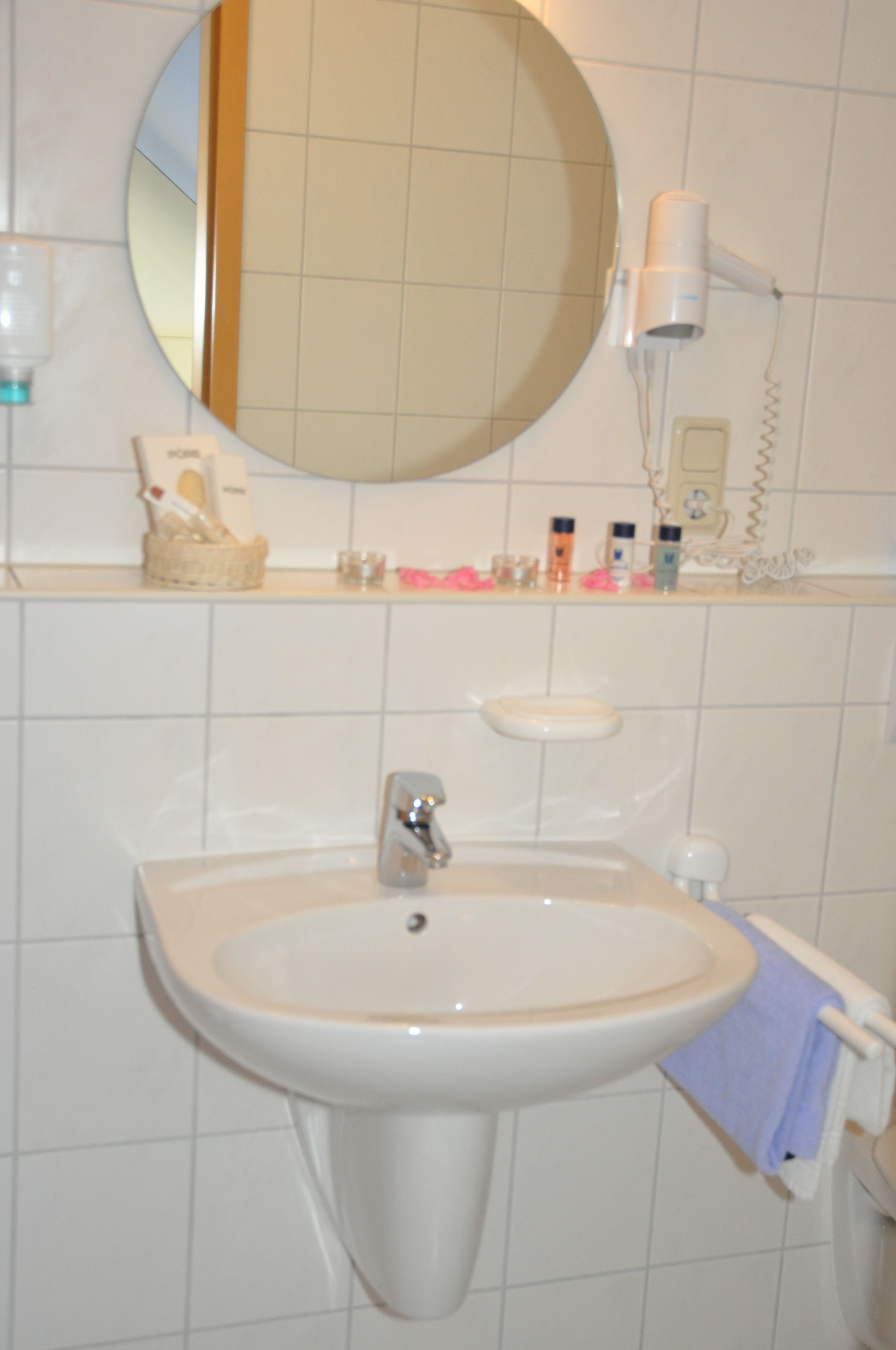 Un baño con lavabo, espejo y secador de pelo en la pared.
