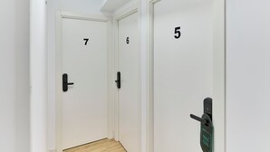 Een gang met drie deuren, genummerd 5, 6 en 7, elk met een modern deurklink.