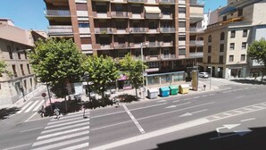 Een meerlaags woongebouw met balkons, een zebrapad en een straat met geparkeerde auto's.