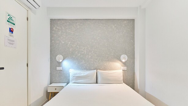 Een slaapkamer met een bed, twee nachtkastjes en een wandlamp.