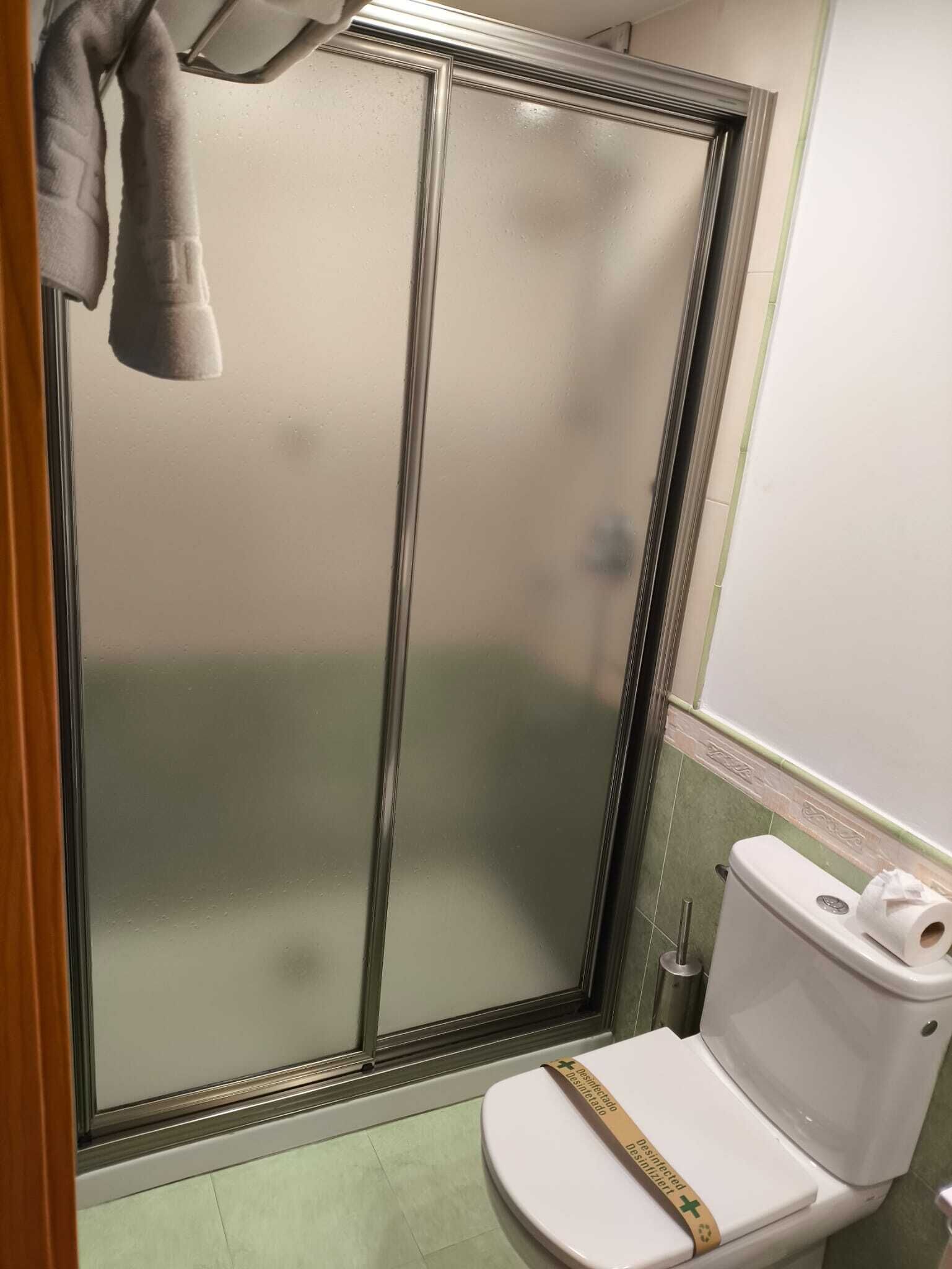 Une salle de bain avec une douche à parois de verre, des toilettes et une serviette accrochée au mur.