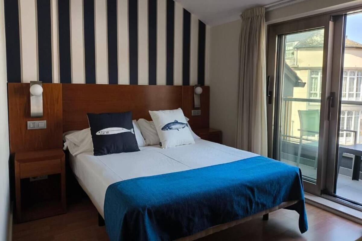 A hotel room with a large bed, striped wall, and a view of the outside.