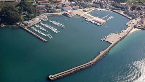 Ein Luftbild einer Küstenstadt mit einem Yachthafen, Stegen und einer langen Pier.