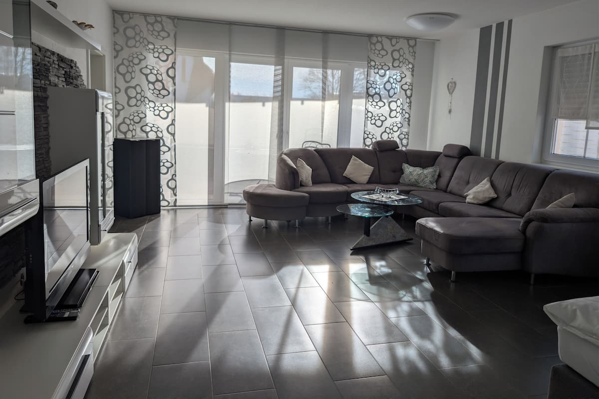 A modern living room with a sectional sofa, a glass coffee table, and a flat-screen TV.