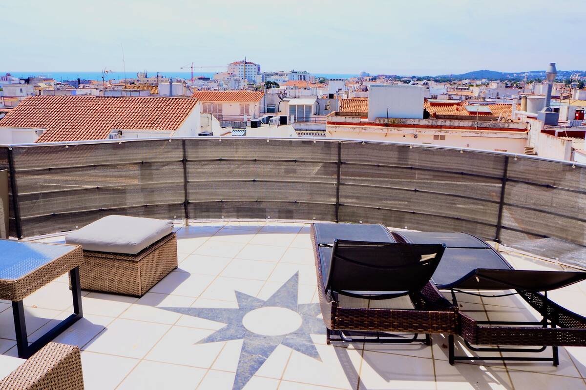 Una terraza en la azotea con mobiliario exterior, suelo con diseño de estrellas y vistas panorámicas de la ciudad.