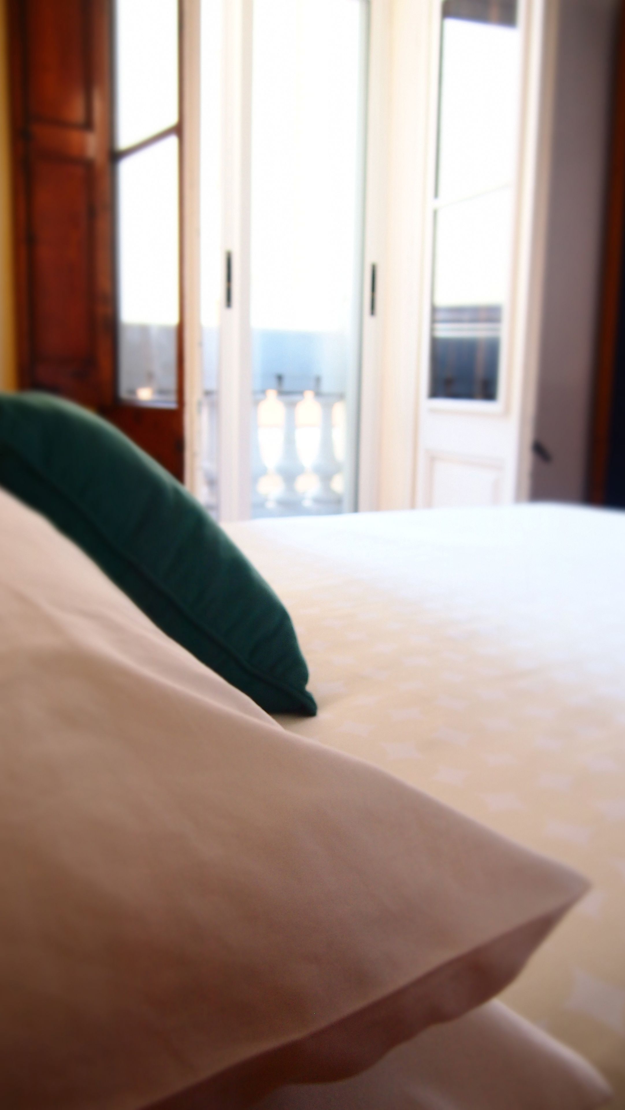 A bed with a green pillow and a white bedspread.