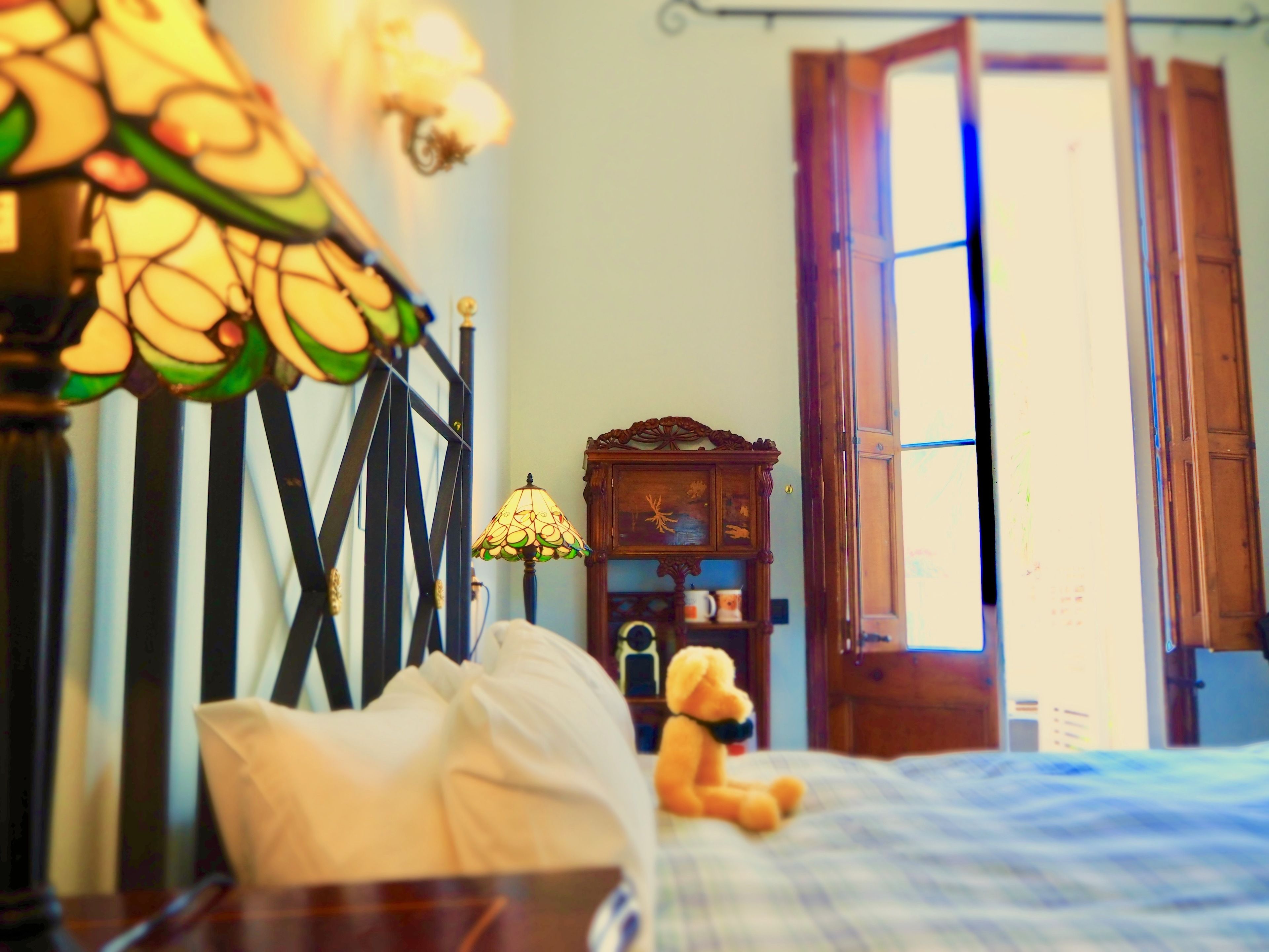 Ein gemütliches Schlafzimmer mit einem Bett, einem Teddybären, einer Lampe und einem Holzschrank.