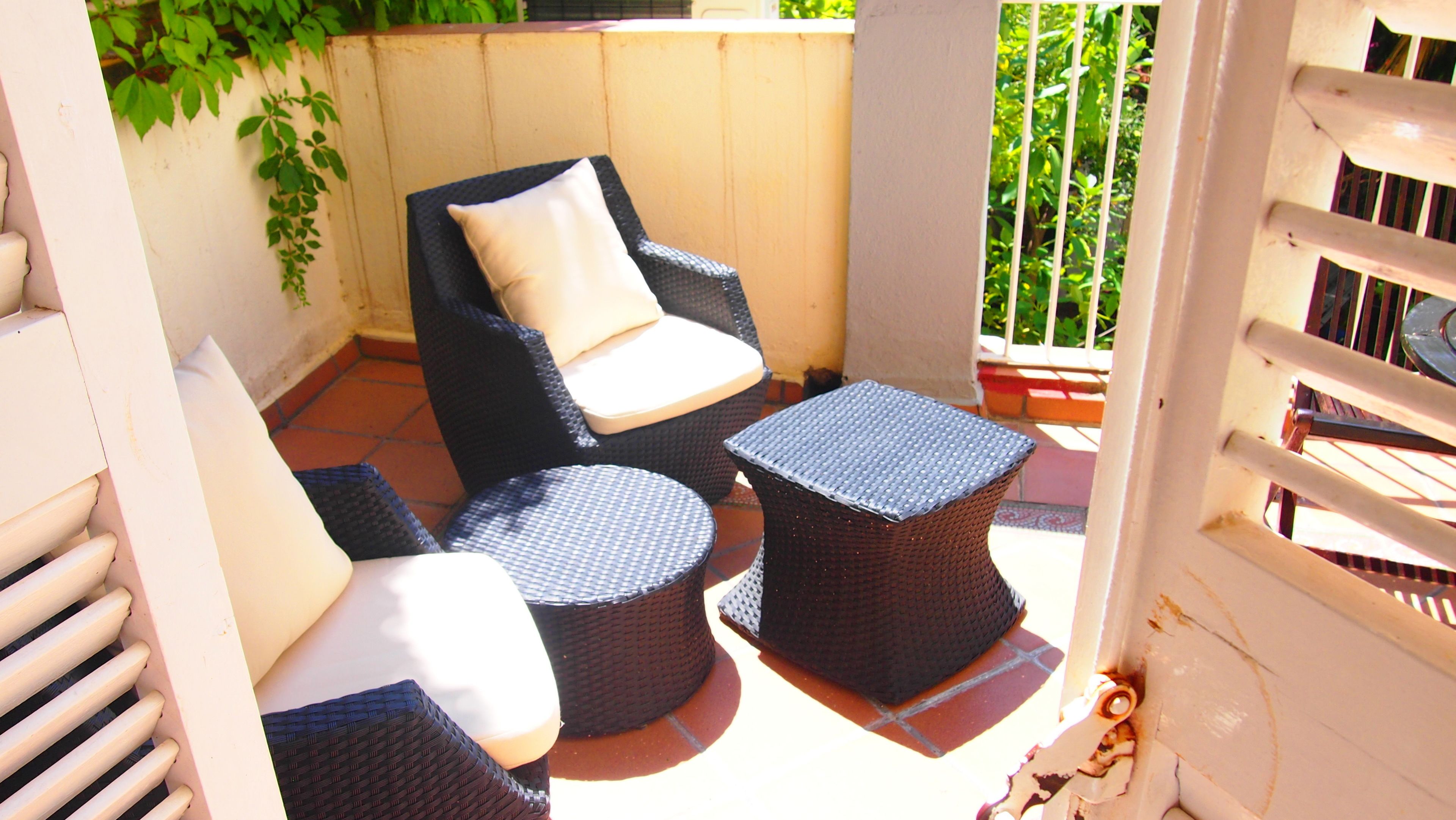An outdoor patio with wicker furniture, including a chair and two round tables.
