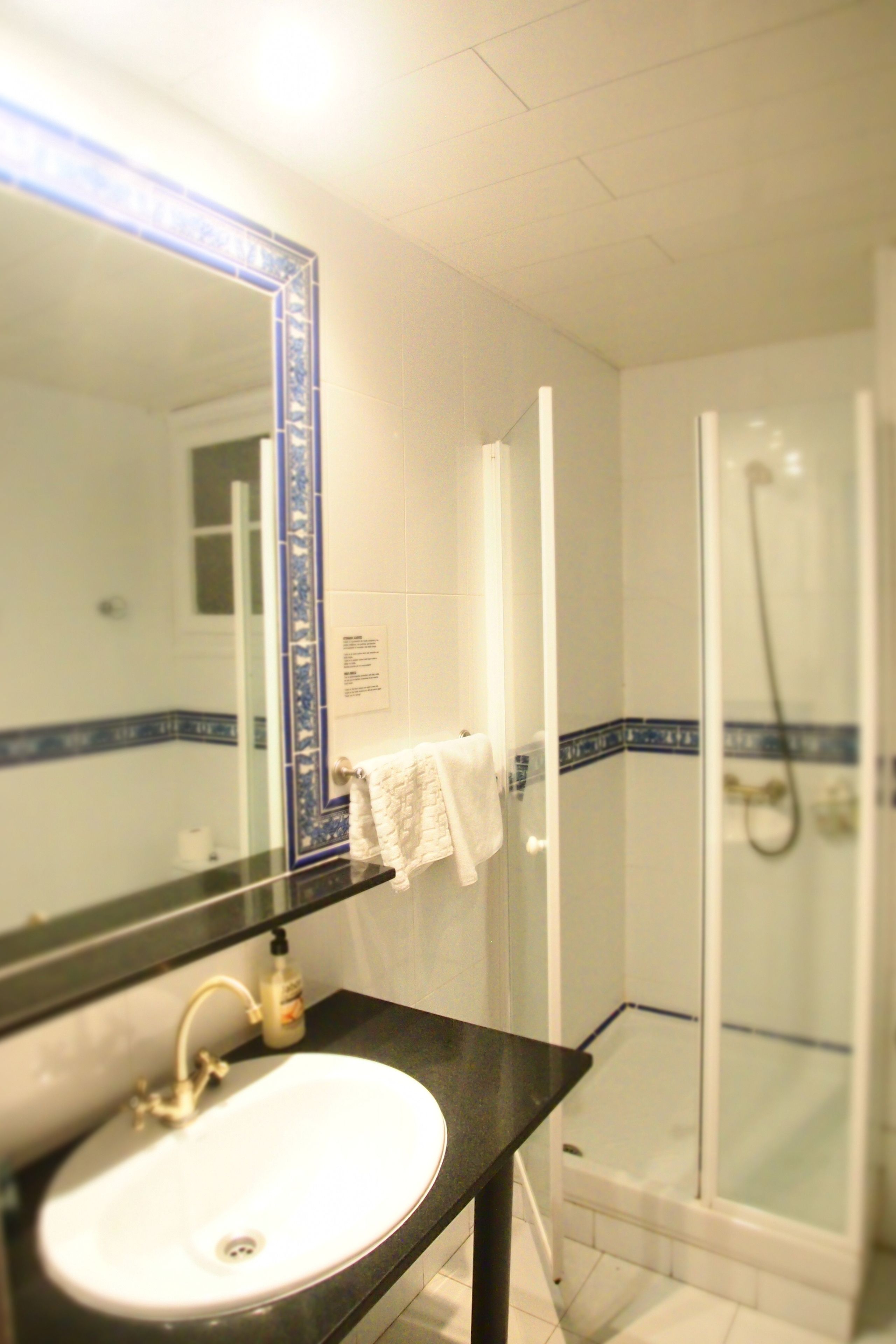 A bathroom with a sink, mirror, and shower.