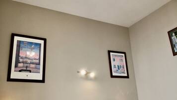 A bedroom with a bed, bedside lamps, a ceiling fan, and framed pictures on the walls.