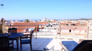 Une terrasse sur le toit, avec une table et des chaises, offrant une vue sur le paysage urbain de la côte.
