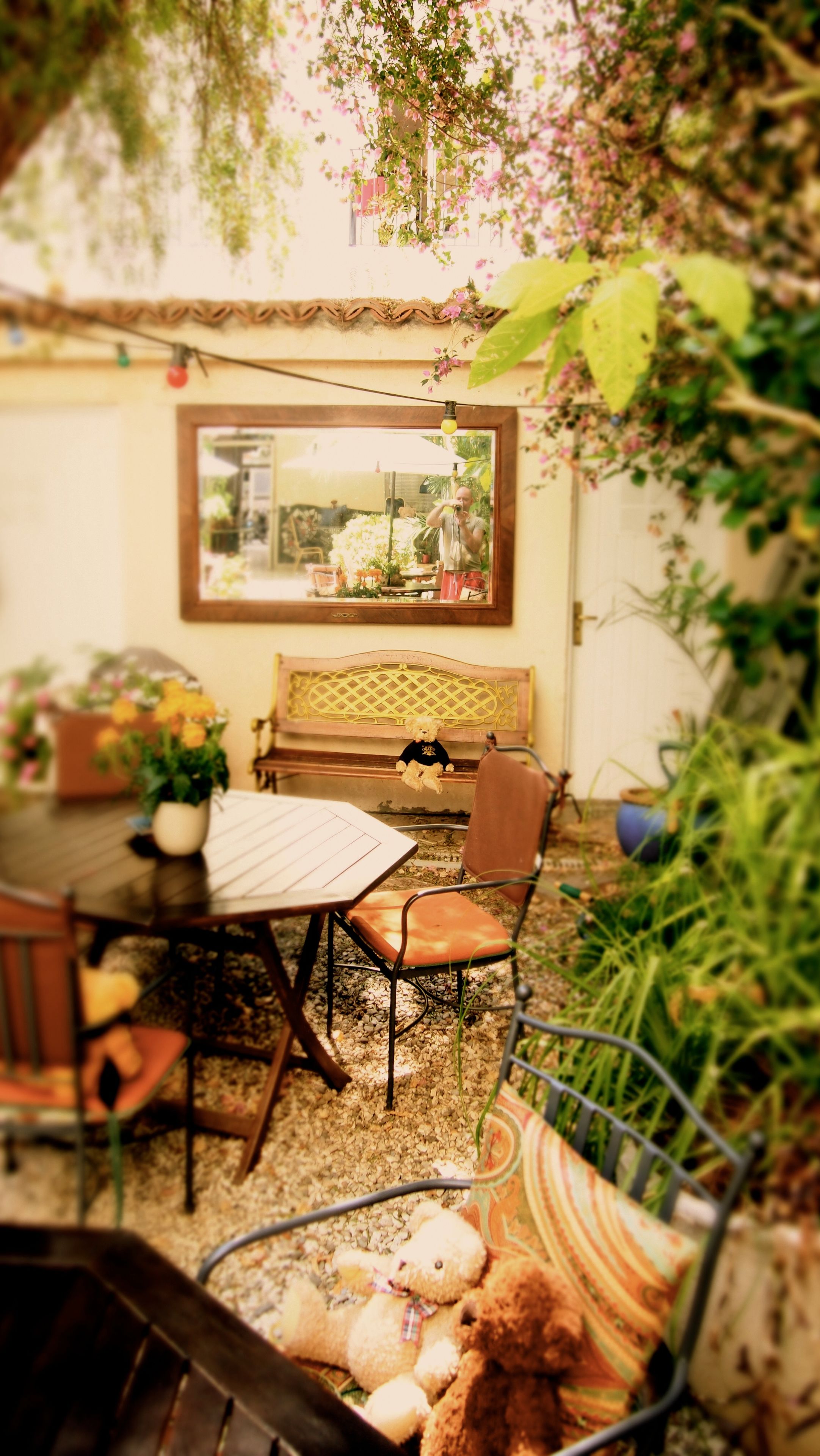 Un patio acogedor con una mesa de madera, sillas, un banco y un oso de peluche.