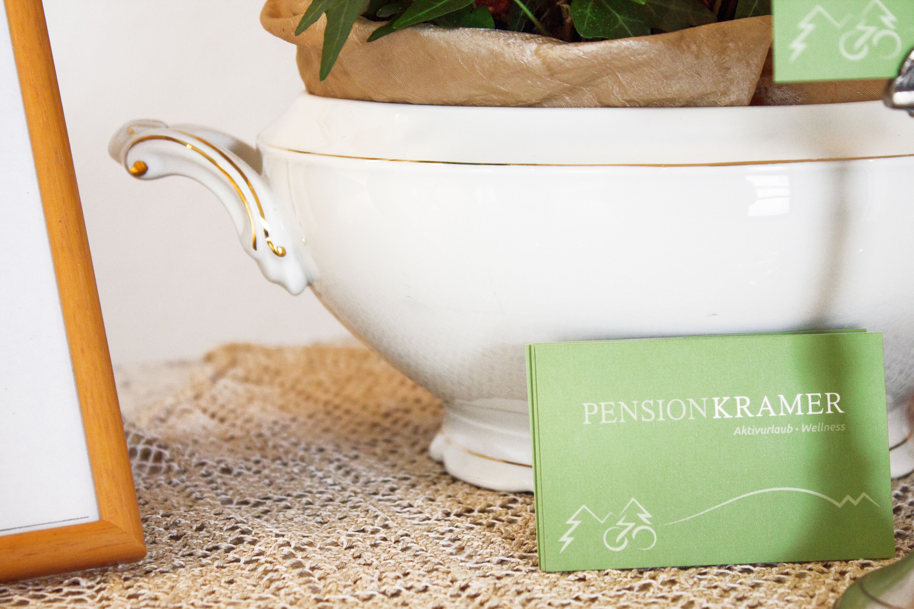 A white teapot with gold trim and a green card beside it.