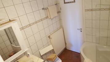 Ein Badezimmer mit einer weißen Badewanne, einem Waschbecken inklusive Spiegel und einem Handtuchhalter.