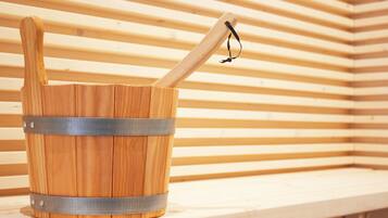A wooden bucket with a metal handle and strap, placed on a wooden shelf.