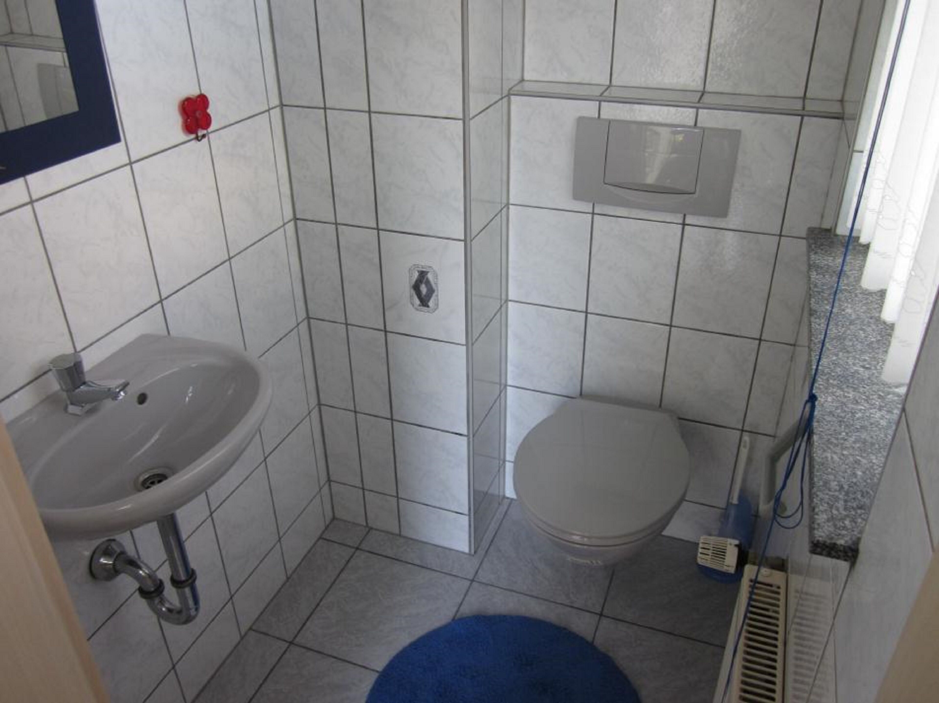 A small bathroom with a sink, toilet, and shower area.
