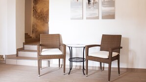 A room with two wicker chairs, a small round table, and a staircase leading to an upper level. - Pension Kramer (Grafenhausen)