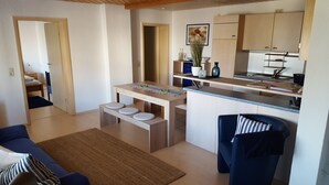 A compact living space with a kitchenette, a dining area with stools, a sofa, and a chair. - Pension Kramer (Grafenhausen)