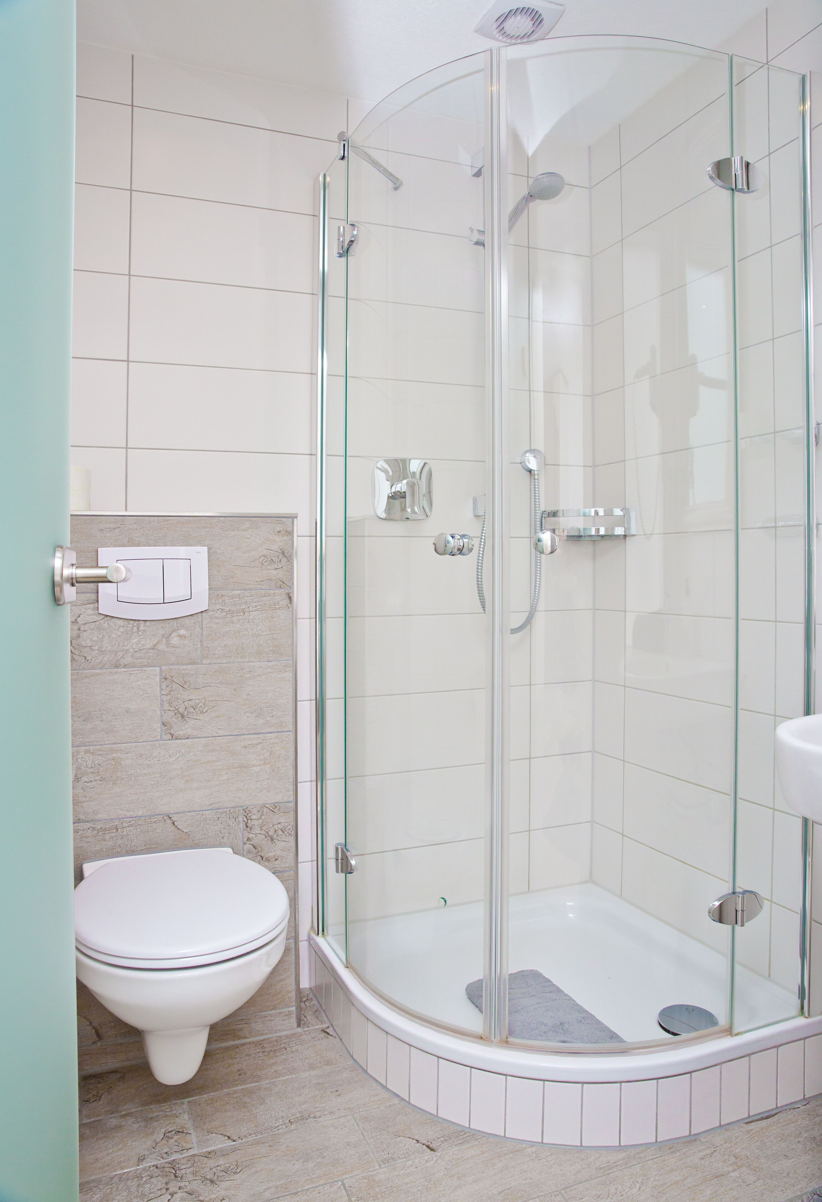 A modern bathroom with a glass-enclosed shower, a white toilet, and a sink.