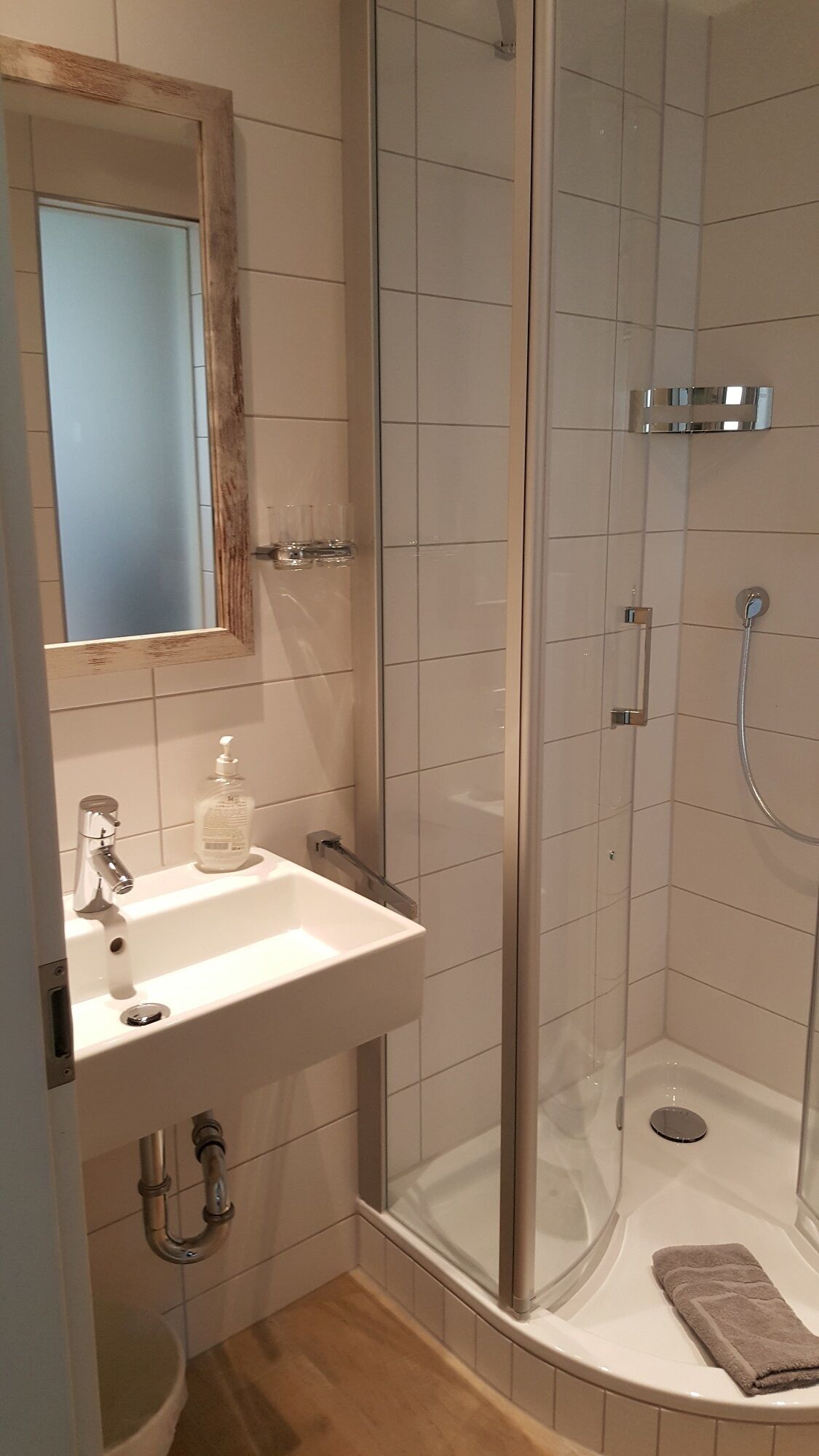 A bathroom with a sink, mirror, and shower.