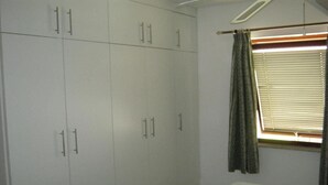 A bedroom with a bed, a wardrobe, and a window with curtains. - Sun Club Premium (San Bartolome de Tirajana)