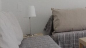 A bedroom with two beds, a bedside table, a lamp, and a wall-mounted light switch. - Sun Club Premium (San Bartolome de Tirajana)