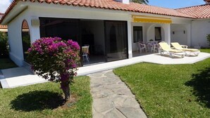 A house with a tiled roof, a covered patio with lounge chairs, and a stone pathway leading to the entrance. - Sun Club Premium (San Bartolome de Tirajana)
