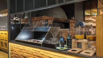 Um balcão de tijolos com uma vitrine de vidro, um forno a lenha e um dispensador de bebidas.