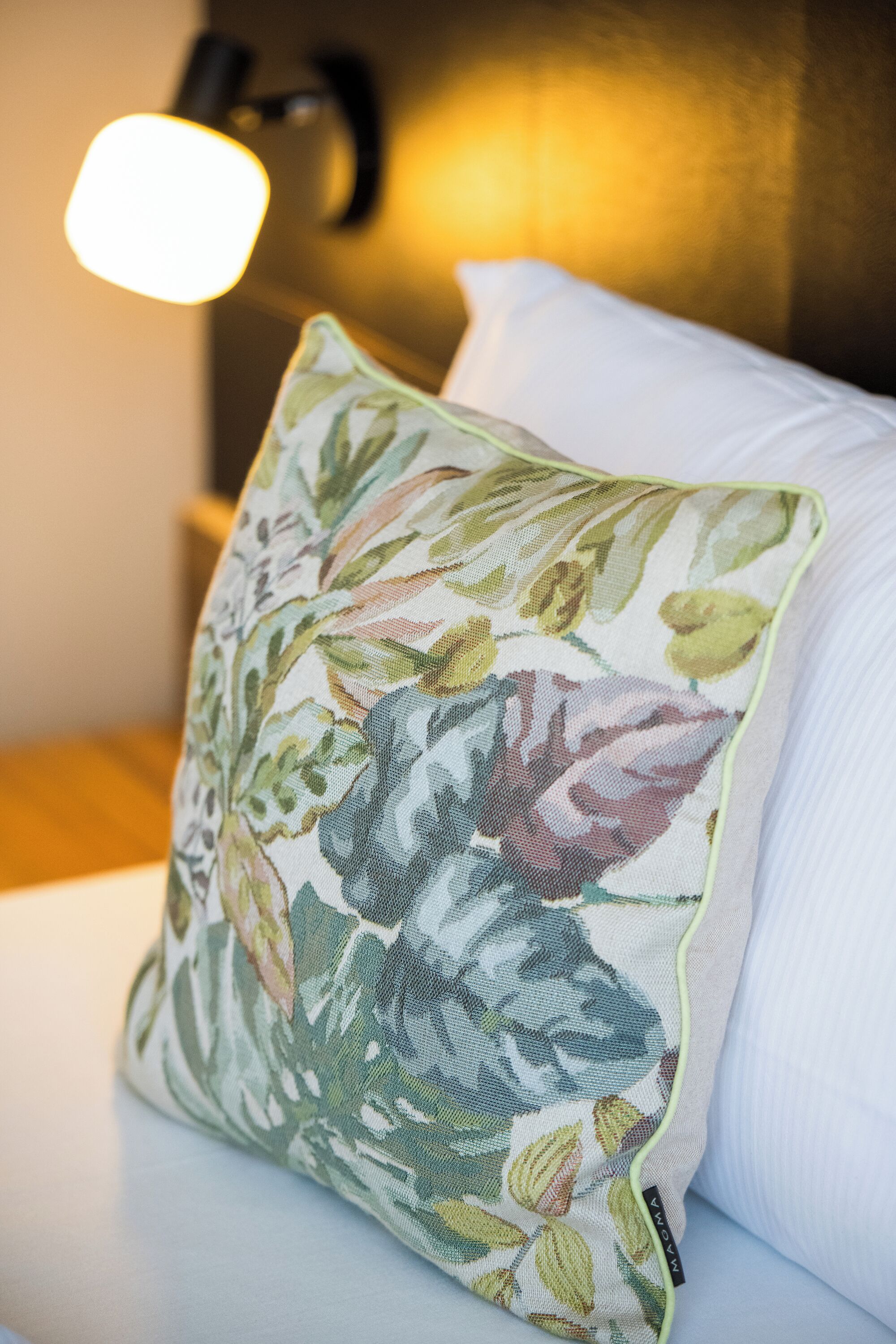 Un almohadón con estampado floral sobre una cama.