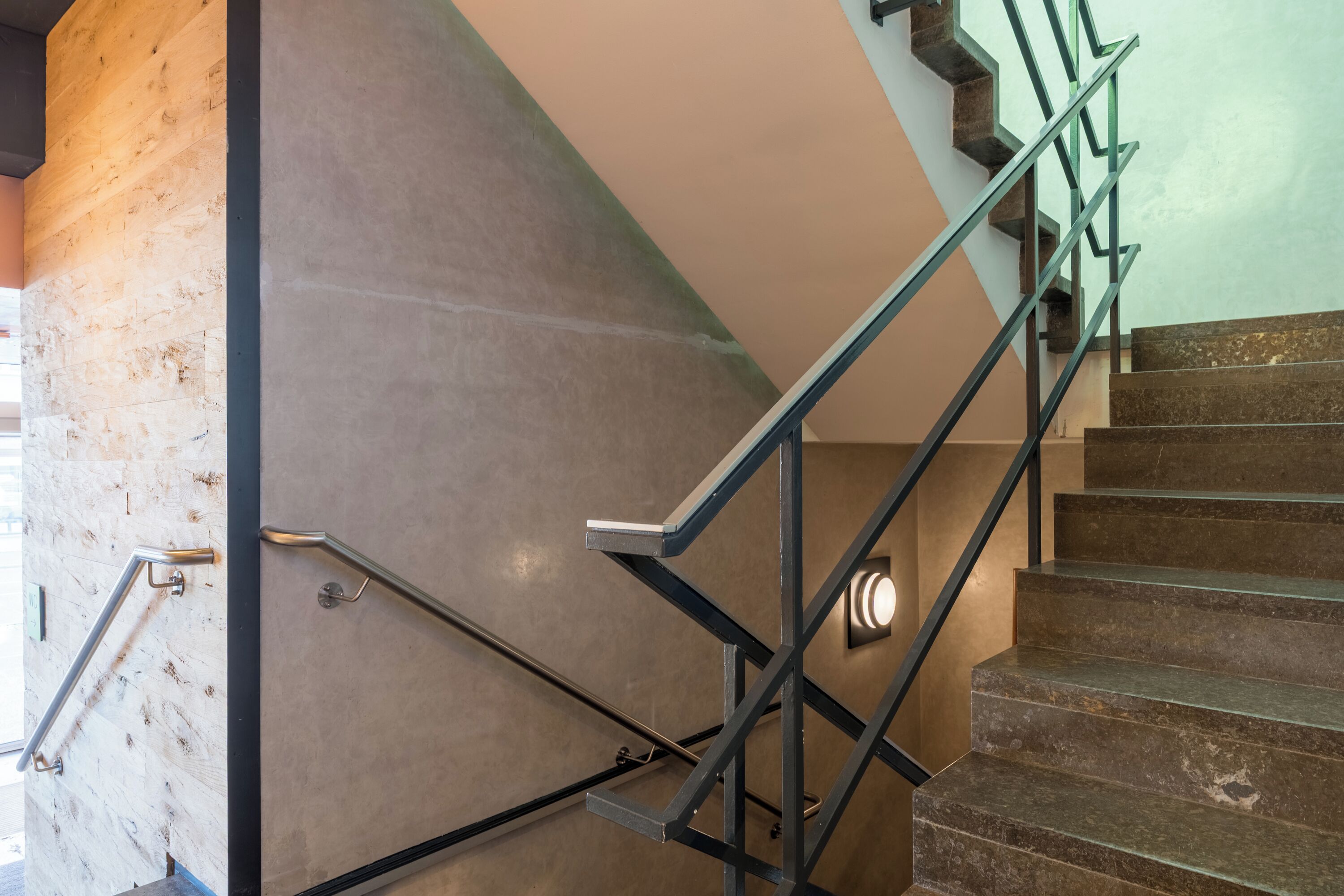 A staircase with metal handrails and a wall with a textured surface.
