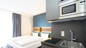 Une chambre d’hôtel équipée d’un lit, d’un four à micro-ondes encastré, d’un lavabo et d’une table de chevet.