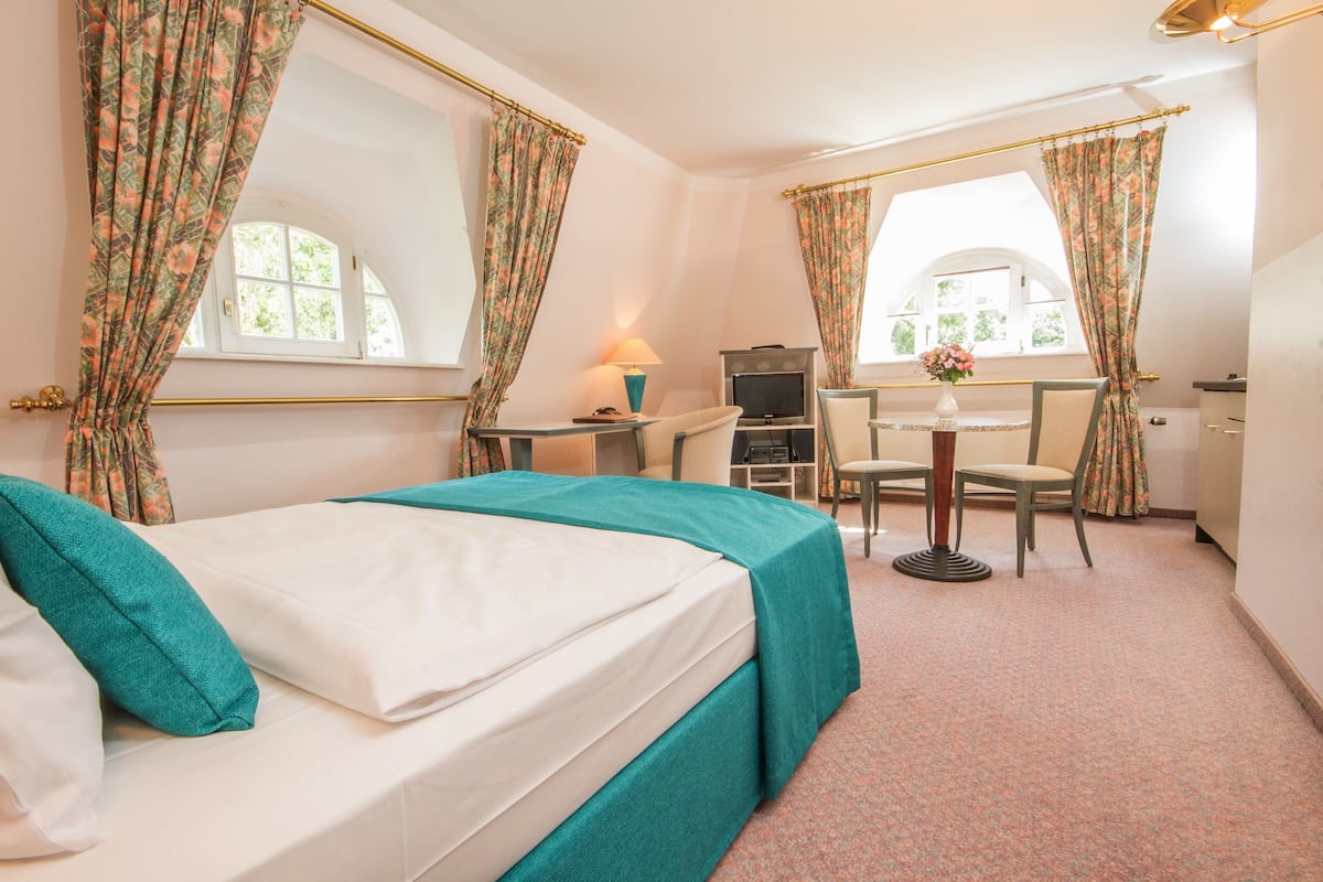 A hotel room with a bed, a desk, a chair, a TV, and a window.