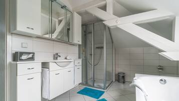 Un baño moderno con ducha, muebles blancos y una alfombra de baño azul.