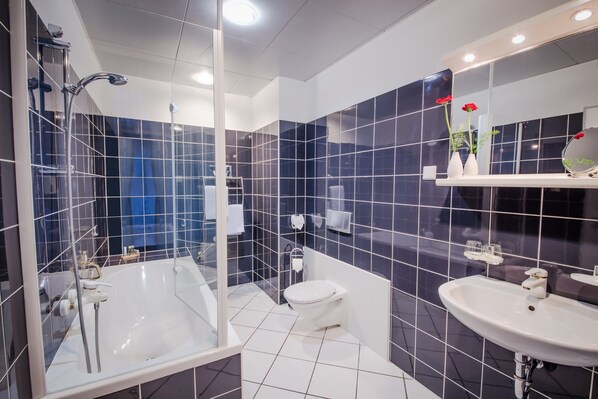 Un baño moderno con ducha acristalada, una bañera blanca y un lavabo con espejo.