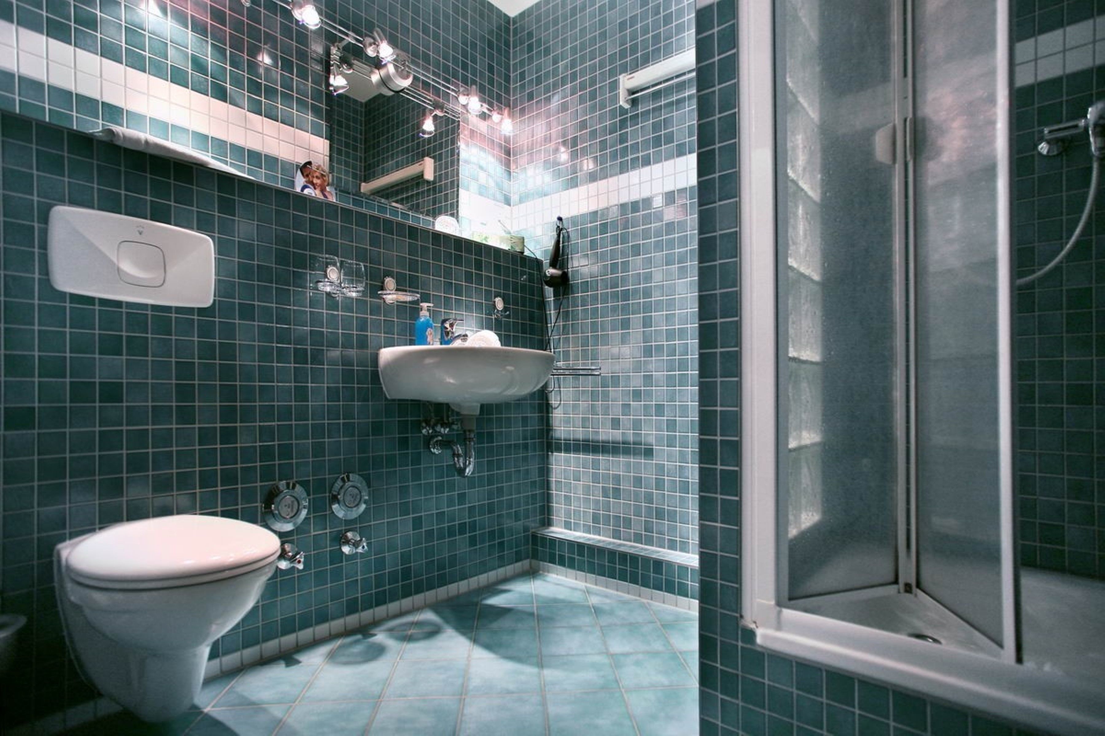 Un baño con inodoro blanco, lavamanos y zona de ducha.