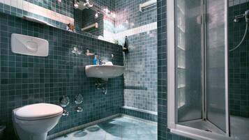 Un baño con inodoro blanco, lavamanos y zona de ducha.