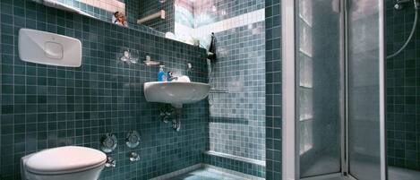 Un baño con inodoro blanco, lavamanos y zona de ducha.