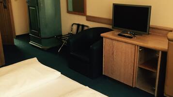 Een hotelkamer met een bed, een bureau met een televisie, een stoel, een kledingkast en een spiegel.