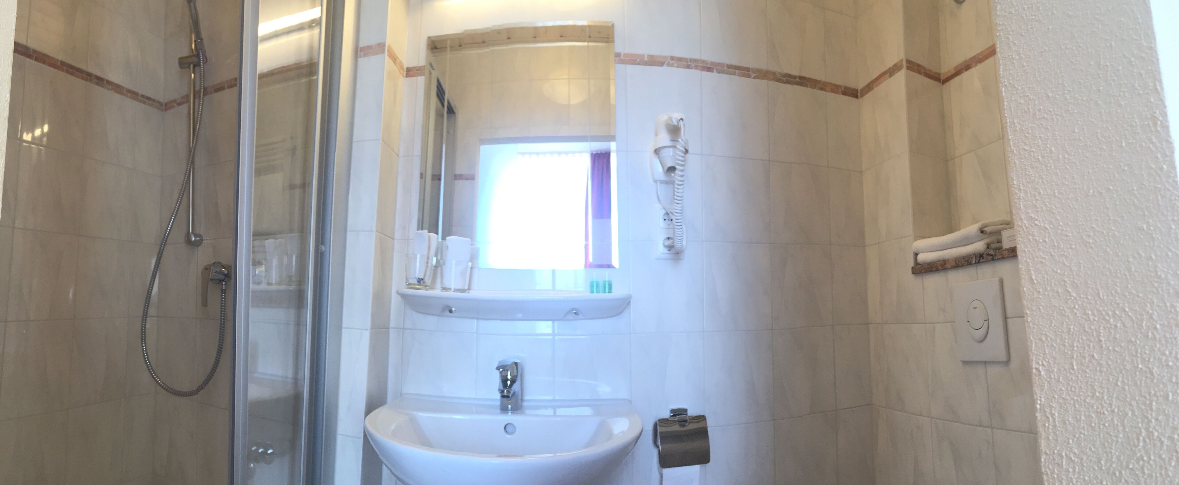 A bathroom with a glass-enclosed shower, a sink, a mirror, and a towel rack.