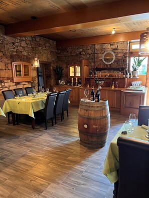 A restaurant with a stone wall, wooden cabinets, and a bar area. - Hotel Gerber (Hoesbach)