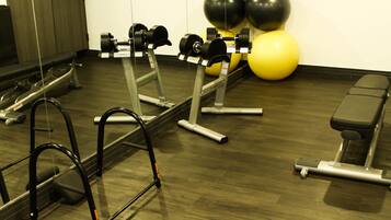 Une salle de sport équipée de matériel d’exercice, d’un banc et de ballons d’exercice.